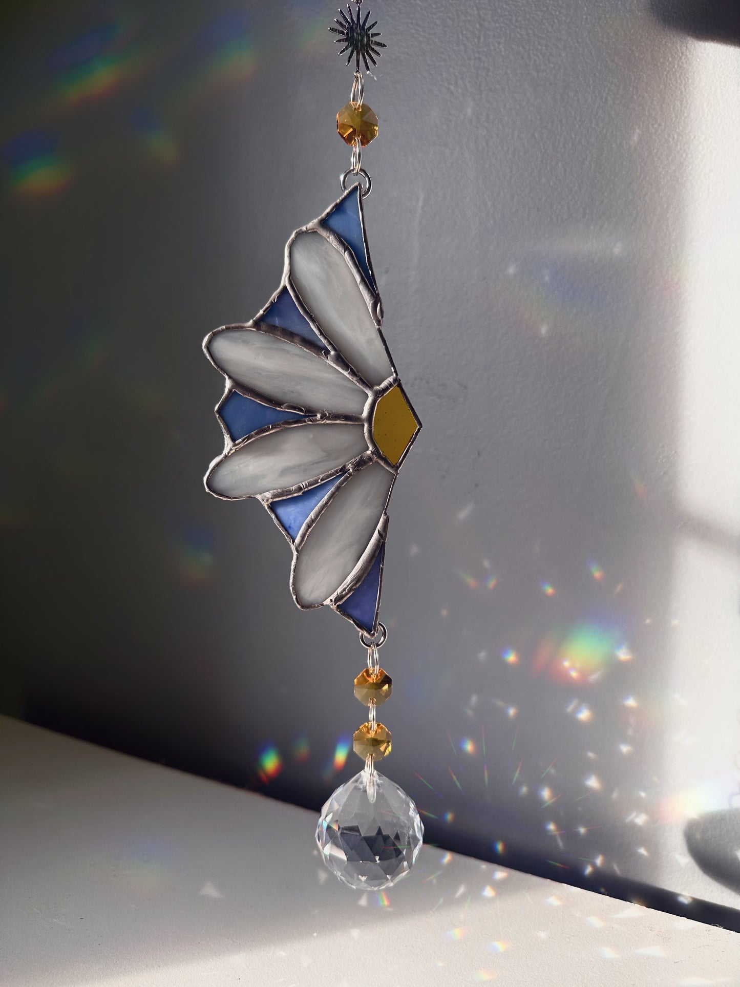 Decorative glass sun catcher with floral design on a reflective surface